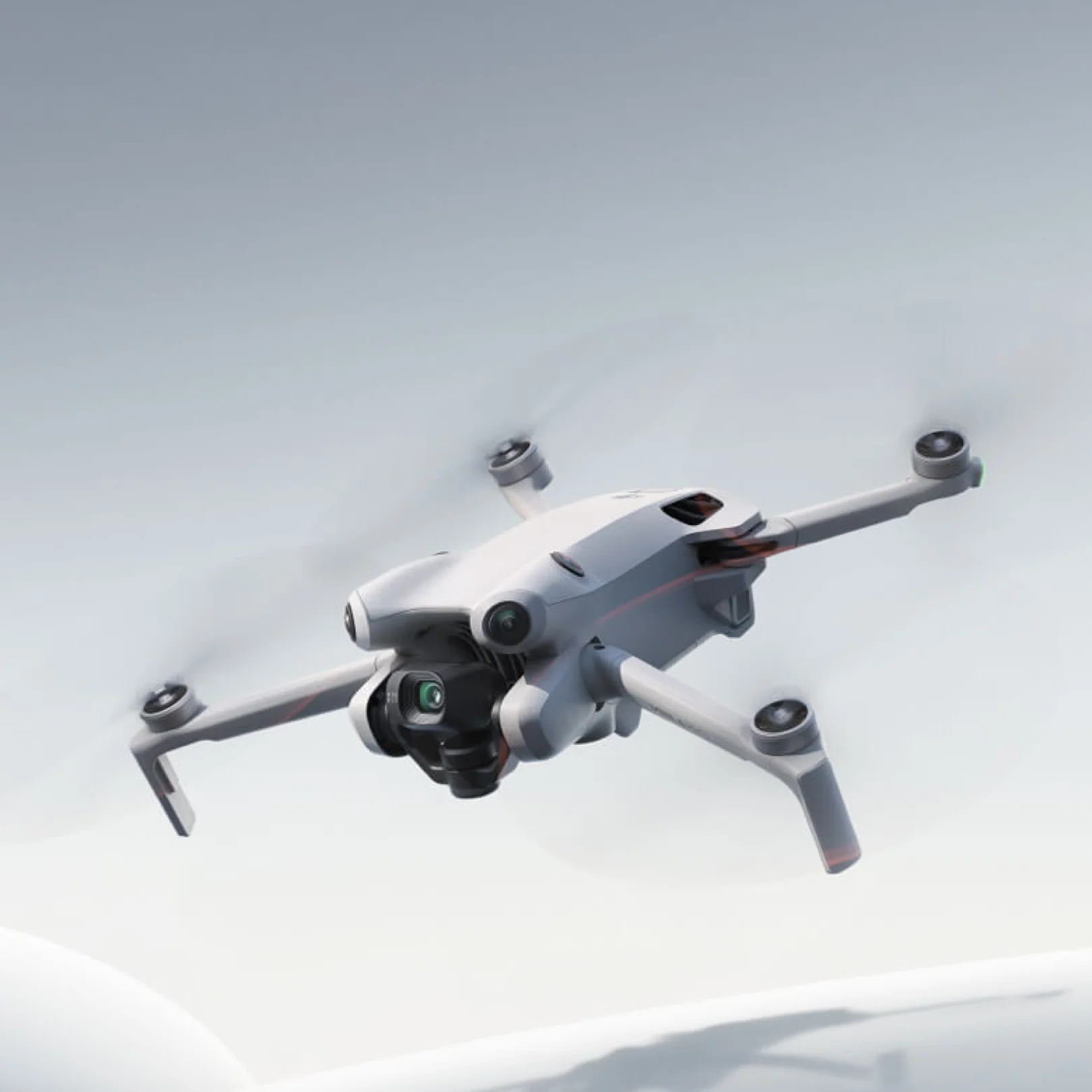 DJI Mini 4 Pro A white DJI Mini 4 Pro drone is shown flying against a light grey and white background, with its propellers blurred from motion. The text