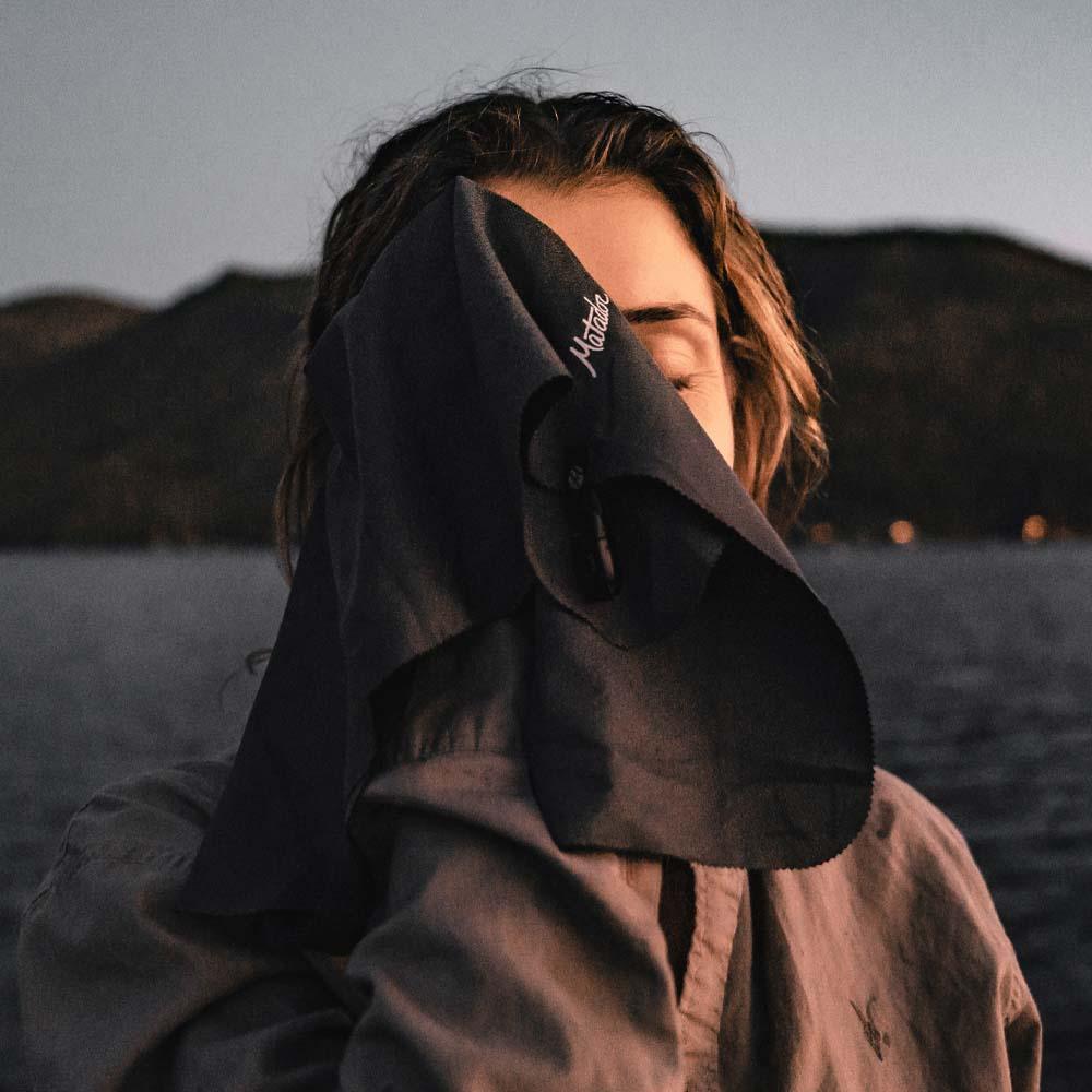 a women wiping her face with Matador Travel Towel