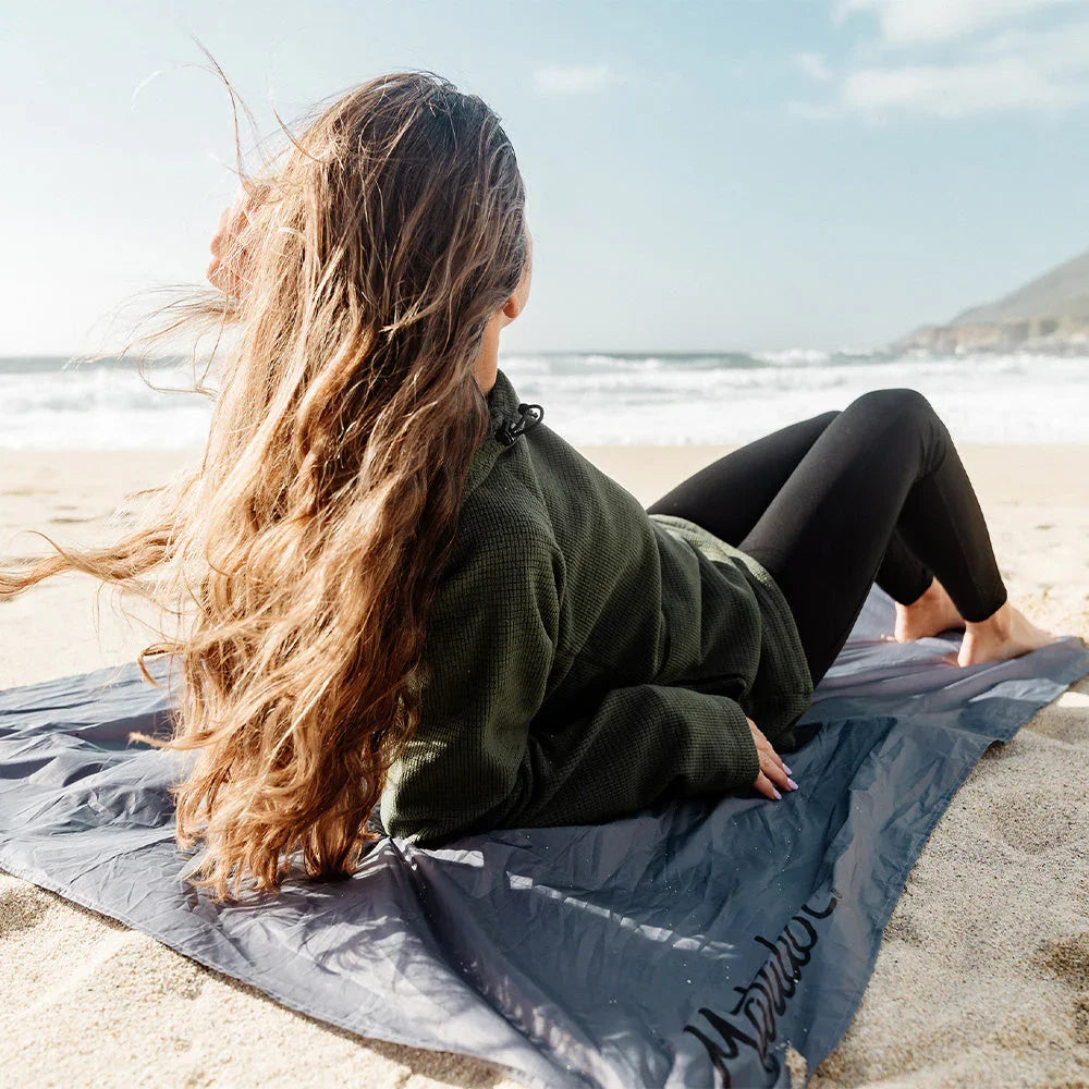 a women lying on a beach using Matador Pocket Blanket