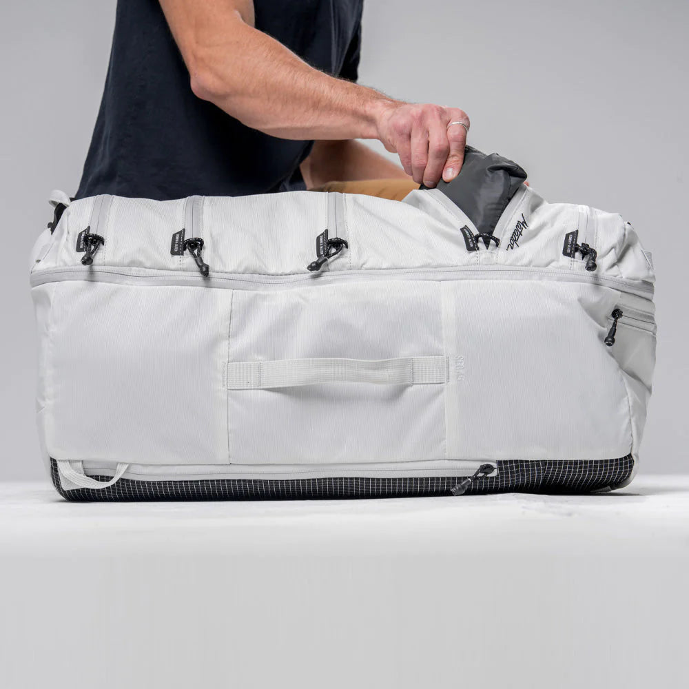 Close up side view of a hand packing with Matador SEG45 Travel Pack white