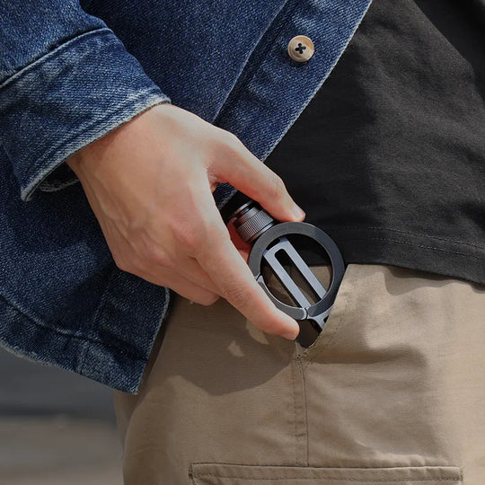 Person holding a black carabiner with a blurred background