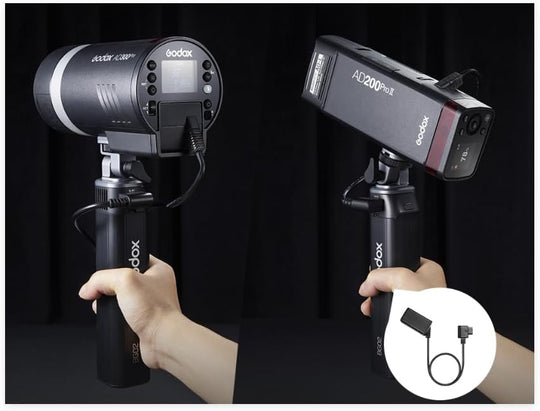 Two Godox studio lights held by hands with a black background