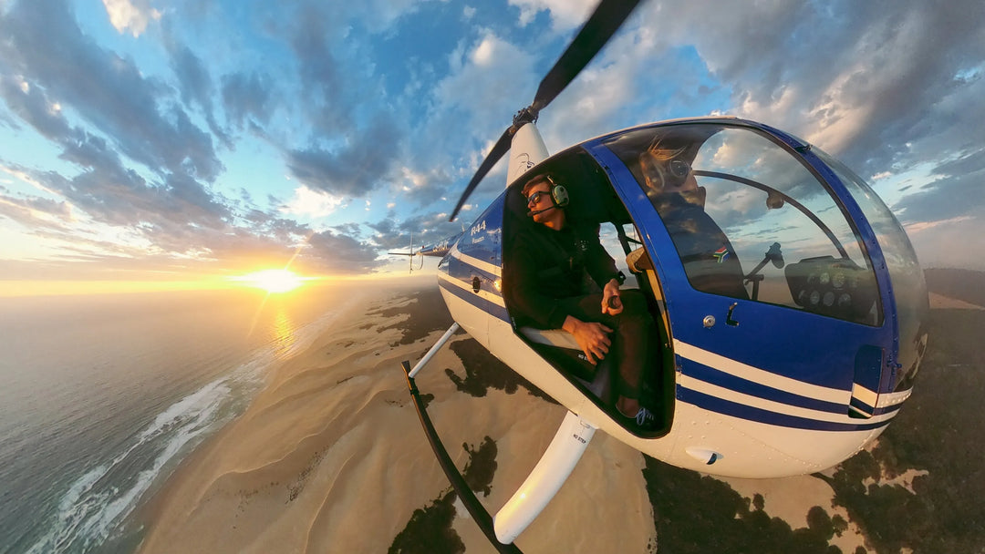 Helicopter flying over a beach with a sunset in the background