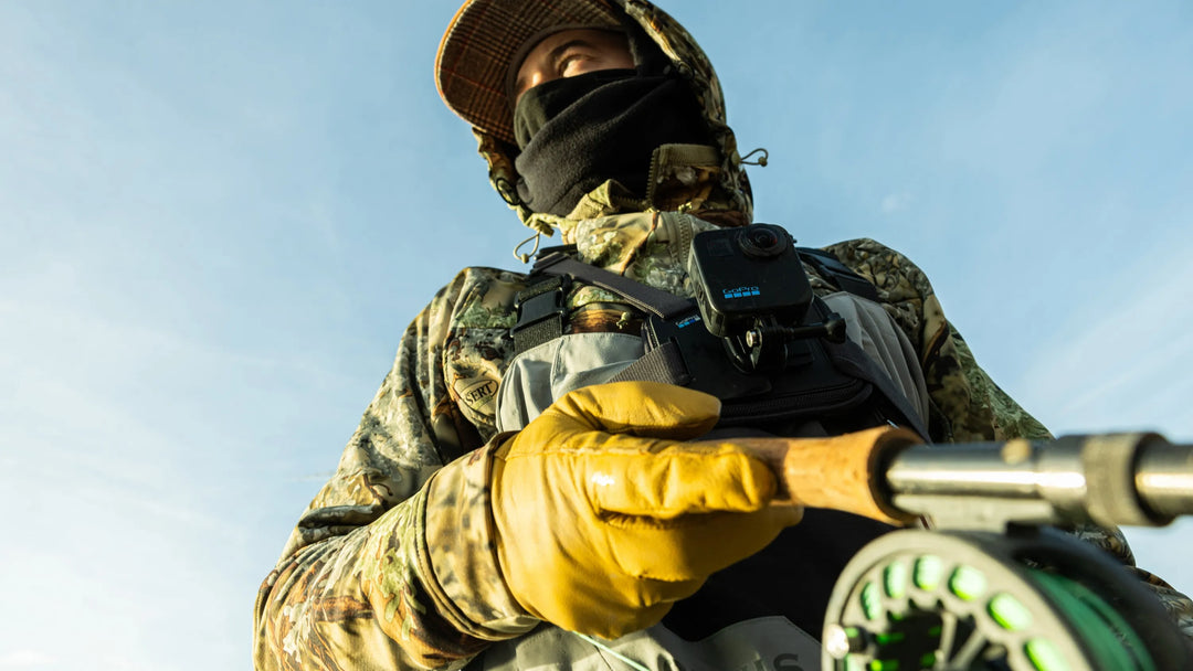 Person in camouflage gear holding a rifle against a clear blue sky