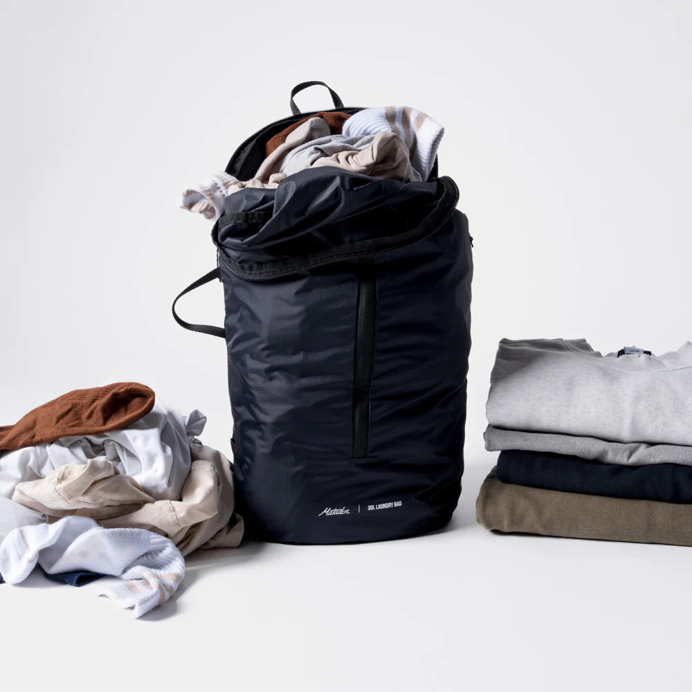Black laundry bag with clothes on a white background