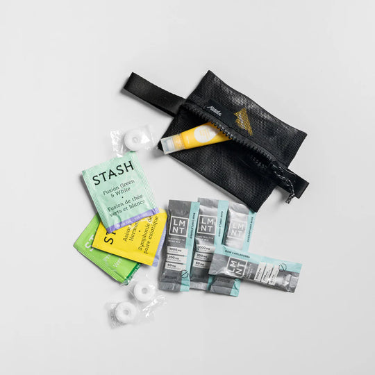 Collection of tea packages and a black mesh pouch on a light gray background