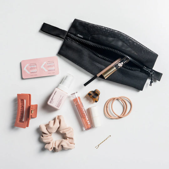 Black matador mash bag with cosmetic items on a light gray background