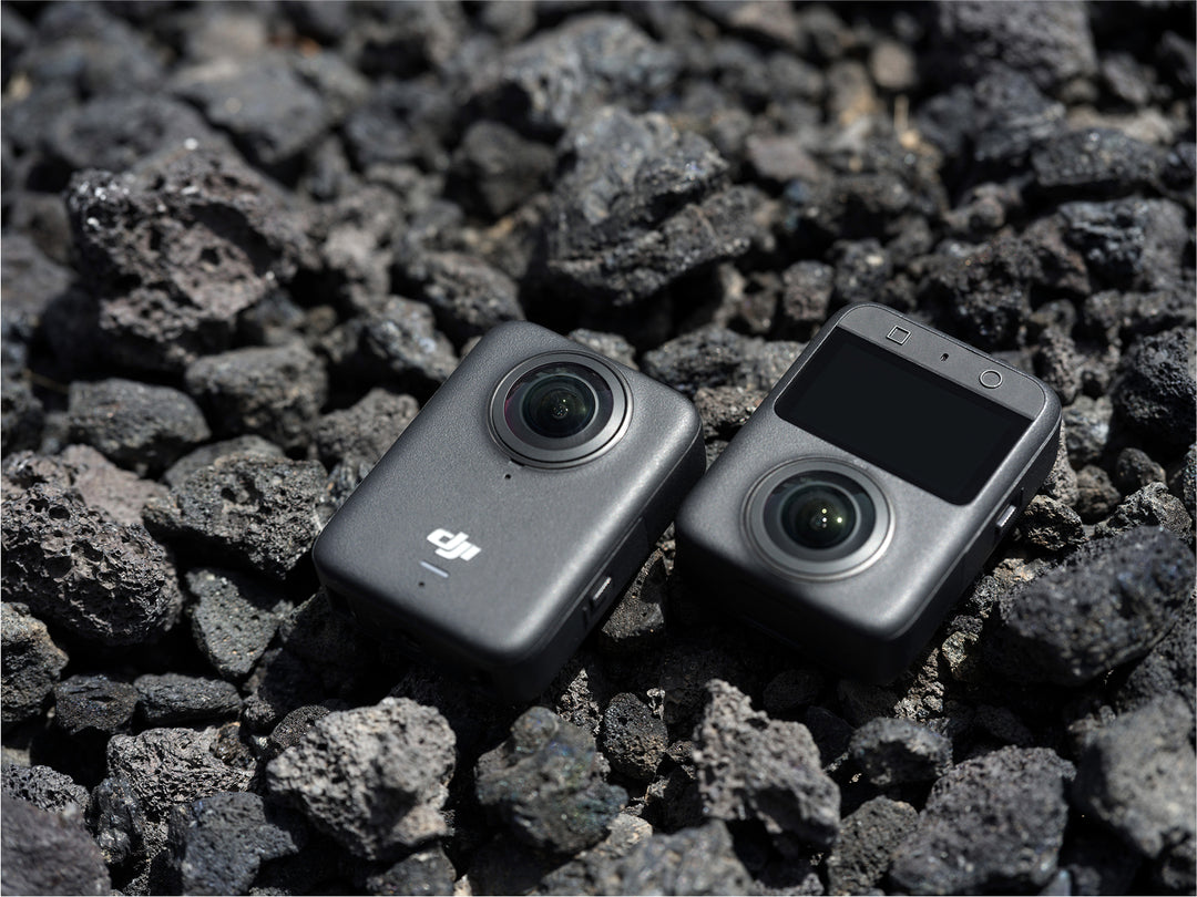 Two cameras on a bed of dark gray stones