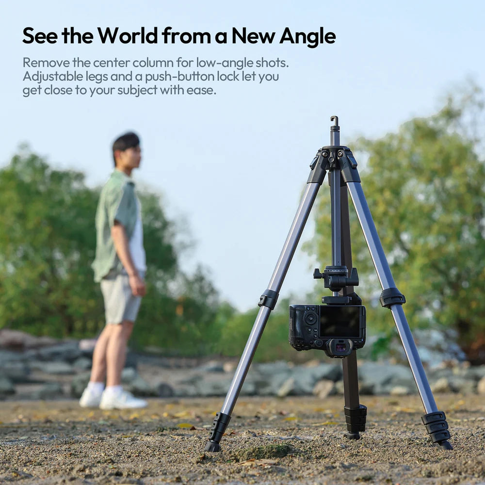 Tripod with adjustable legs and push-button lock in a natural setting with a person in the background.